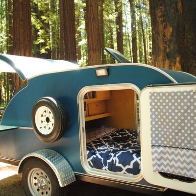 Teardrop travel trailer with open doors and view to bedroom.