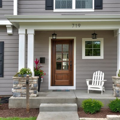 Attractive gray and white house with black shutters; house number and mailbox on front porch.