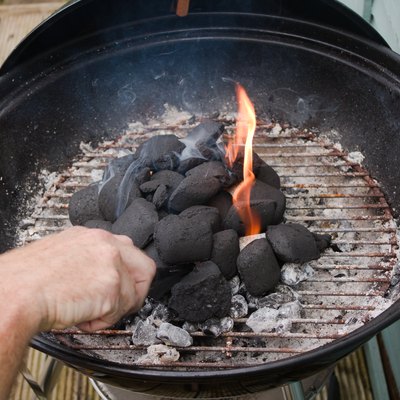 Lighting charcoal briquettes in grill.