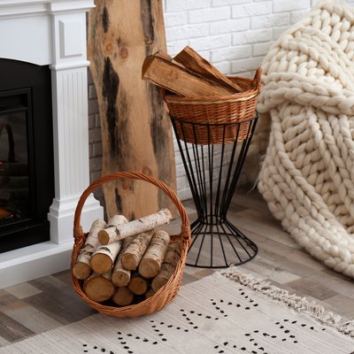 Wicker baskets with firewood and burning fireplace in cozy living room
