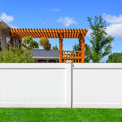 Partial view of solid white vinyl fence between yards