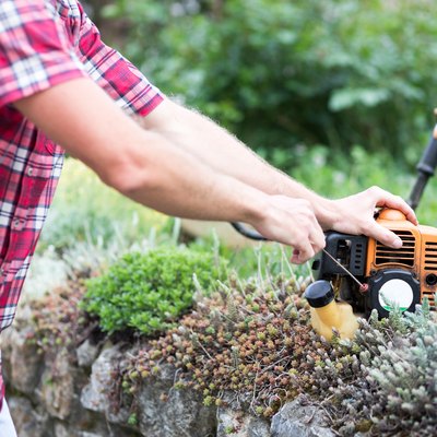 Close-up of a young man starting a string trimmer