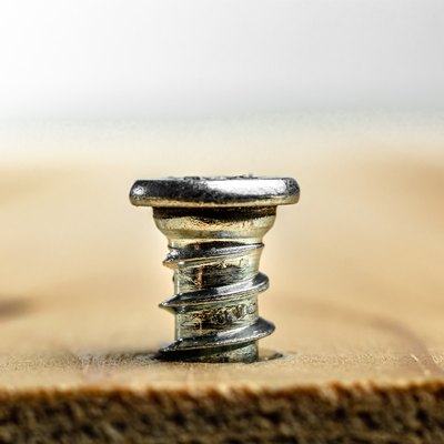 Closeup of screw being screwed into a wooden plank - macro shoot - white background