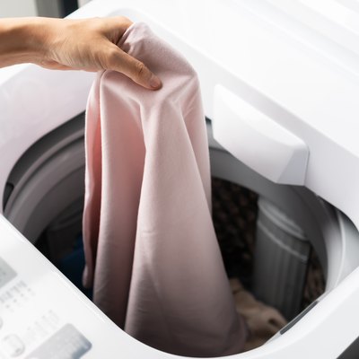 Putting  clothes in washing machine.