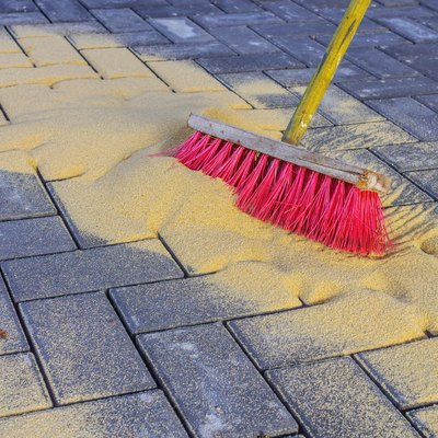 Sweeping in joint sand on a construction site.