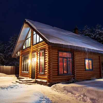 Rustic log house, snow-covered pine trees, snowdrifts, fabulous winter night.