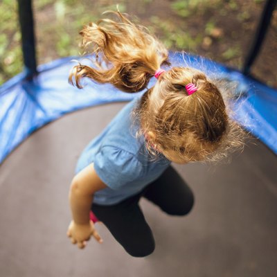 Kid jumping on a trampoline on a summer day.