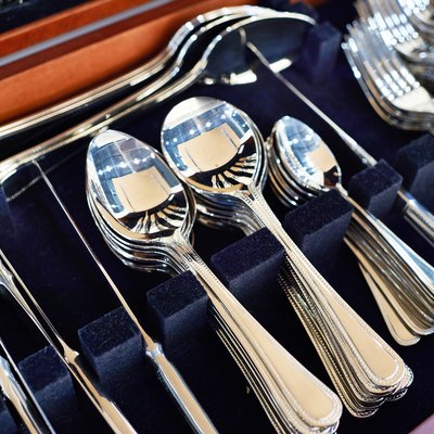 Forks, spoons, and knives in a case line with dark-blue velvet.
