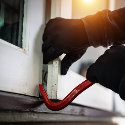 dangerous masked burglar with crowbar breaking into a victim's home door,concept