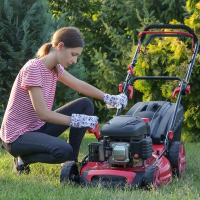Woman checking lawn mower oil.