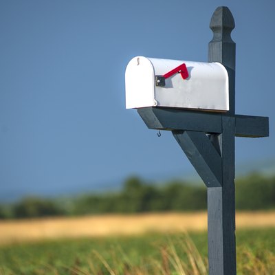 White Rural Mailbox With Red Flag On Blue or Gray Post