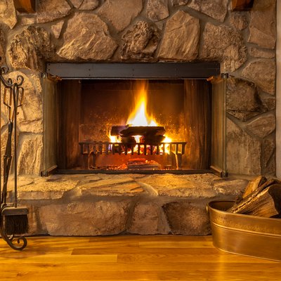 Stone fireplace with logs burning in a residential home.