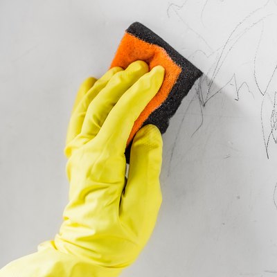 Cleaning child's pencil drawings off a white wall.