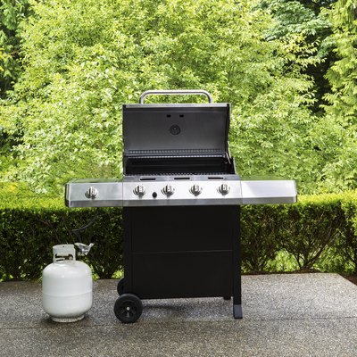 Large outdoor bbq cooker with white propane tank on home concrete patio