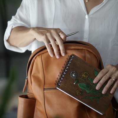Woman with leather bag, pen, and notebook.