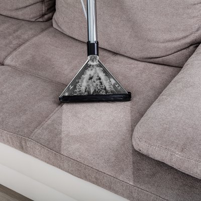 Woman Cleaning Sofa With Vacuum Cleaner