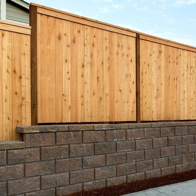 Wood fencing on concrete or stone retaining wall of home.