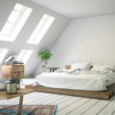 White loft bedroom with slanted wall and dormer windows..