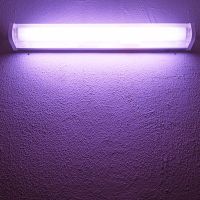 Germicidal ultraviolet lamp glows on a rough wall.