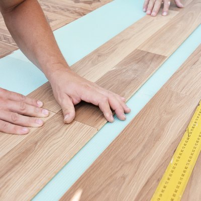 Wood laminate flooring installation: Laminate flooring installers are installing laminate hardwood planks over a soundproofing underlayment, insulation.