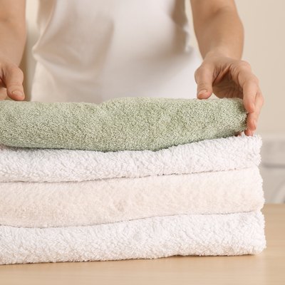 Woman with folded clean terry towels at table in laundry room, closeup