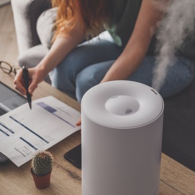 Woman freelancer uses a household humidifier in the workplace at home office with a laptop and documents.