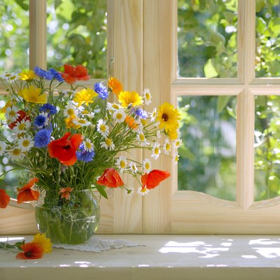 Bright summer bouquet in glass vase on a sunlit windowsill.