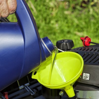 A man pours oil on his lawn mower