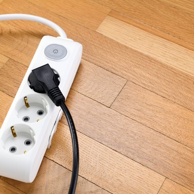 White extension cord with three outlets on wood floor