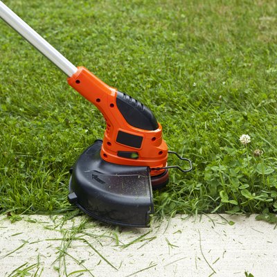 Weed Trimmer Trimming Grass Along Sidewalk