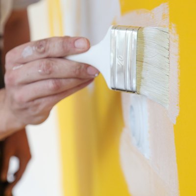 Painting with white paint over a yellow wall
