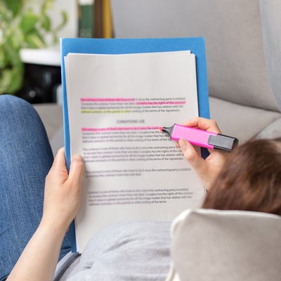 Woman studying via highlighting in a notebook.