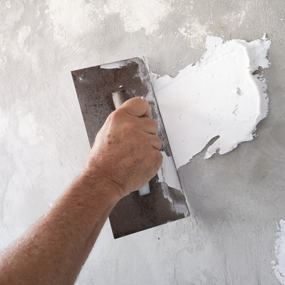 Using plastering tool for finishing old wall.