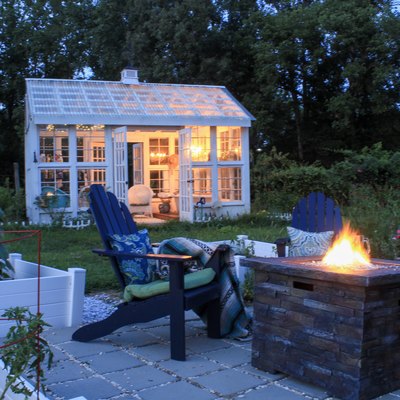 Beautiful garden with fire pit andirondack chairs and greenhouse