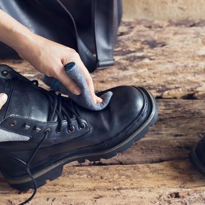Cleaning boots on wooden background.