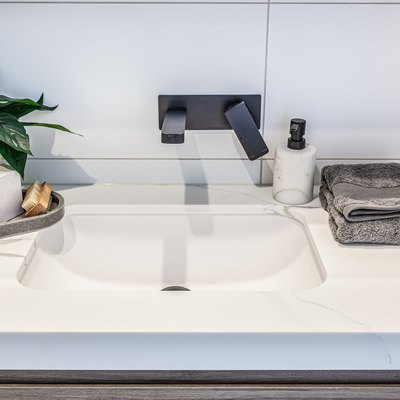 Closeup of modern white washbasin with black faucet