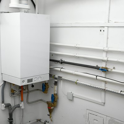 Corner of a room with white boiler and connectors