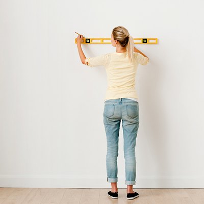 Woman using a spirit level on wall.