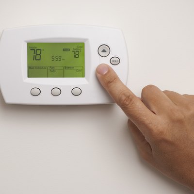 Male hand on digital thermostat set at 78 degrees