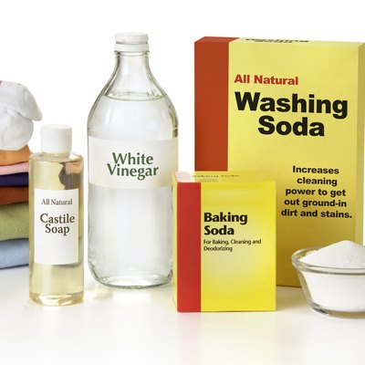 Washing soda, Castile soap, white vinegar, baking soda beside a stack of clean, folded laundry