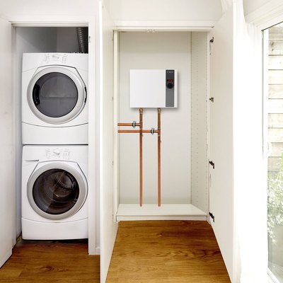 A laundry room with a tankless water heater installed next to it
