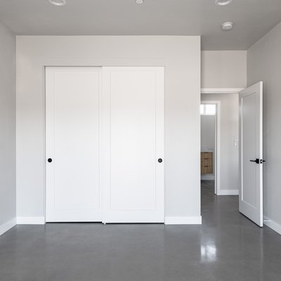 Light gray wall room with white sliding closet doors and dark gray flooring