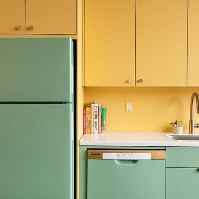 A green painted refrigerator and dishwasher and yellow upper cabinets