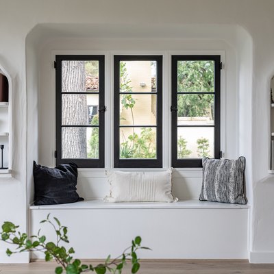Three skinny windows with black trim above a built-in bench and built-in bookshelves