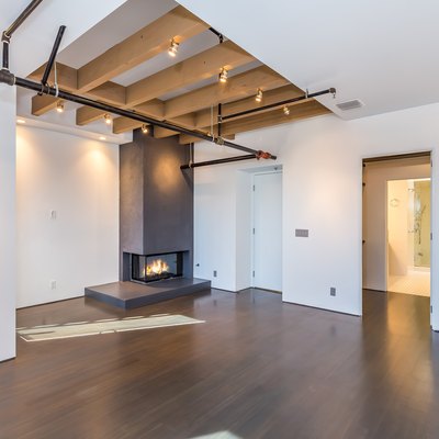 Accent wood beams in a ceiling over a fireplace in a room with dark wood flooring