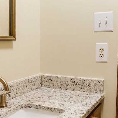 Beige walled bathroom with a light switch and double wall outlet