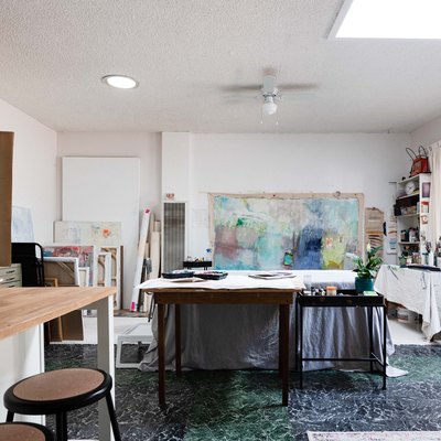Garage Ideas in Artist gallery with white walls, with large painting attached to one wall, next to shelves with painting supplies and small kitchen island with brown stools