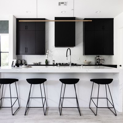 Modern kitchen with black cabinets, white counters and black stools