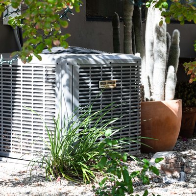 An outdoor air conditioner shaded by plants