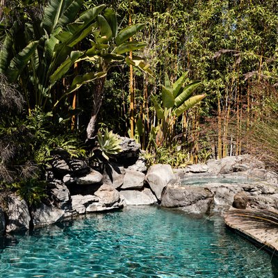 An in-ground pool surrounded by rocks and a natural green setting
